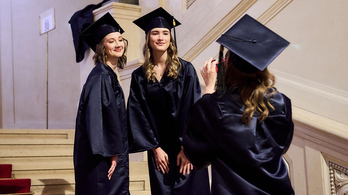 graduates posing for photos together, Webster University in Vienna commencement 2025